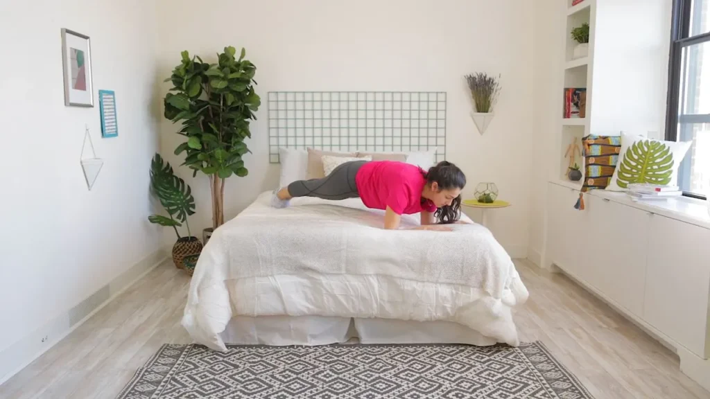 woman doing plank on a bed