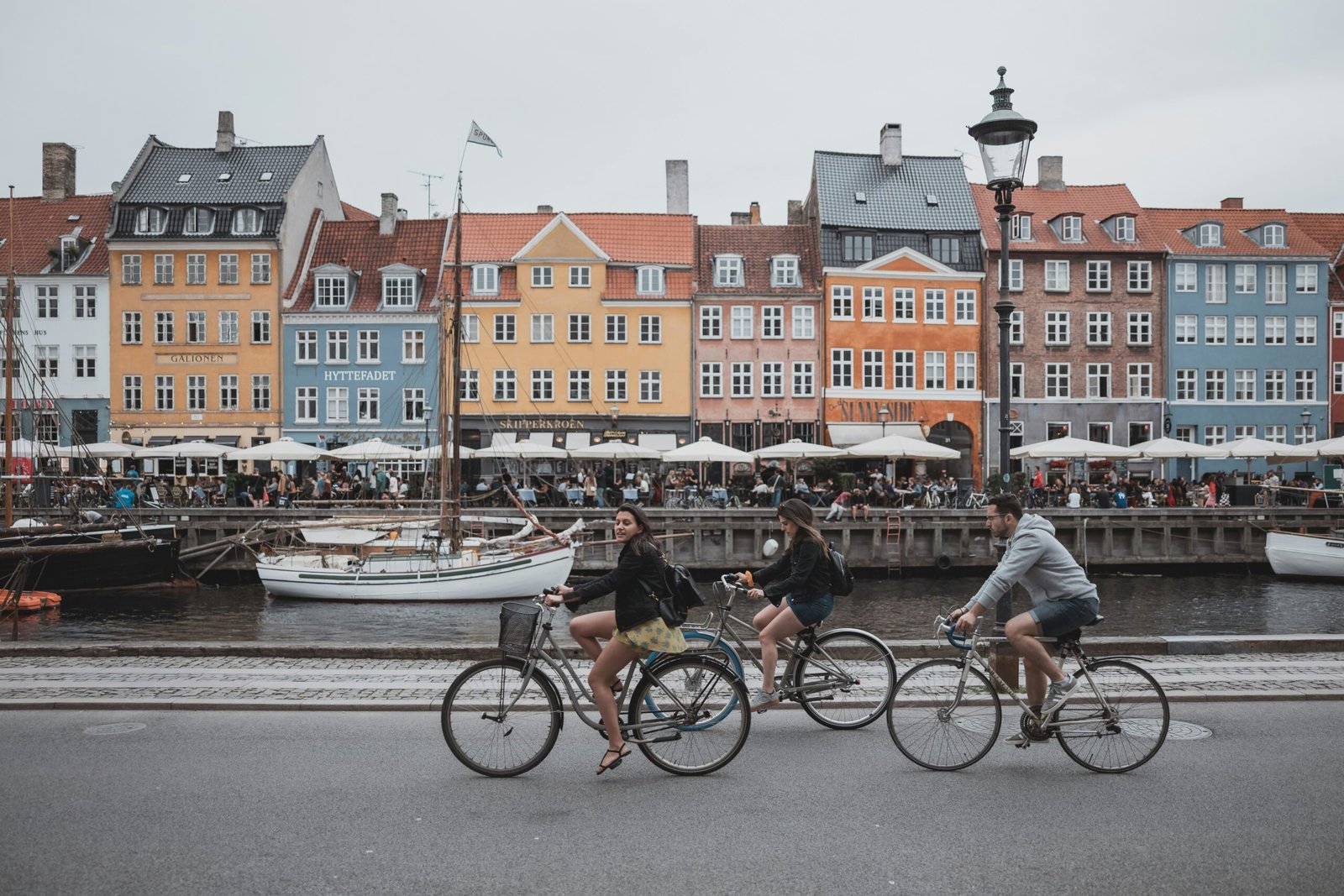 Cyclists riding through Nyhavn in Copenhagen, showcasing the city’s vibrant bike culture and scenic urban landscape.